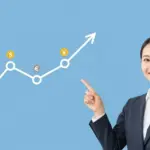 笑顔の公務員がドルコスト平均法のグラフを指さす。投資初心者でもリスクを抑えて安心して資産運用を始めるイメージ。